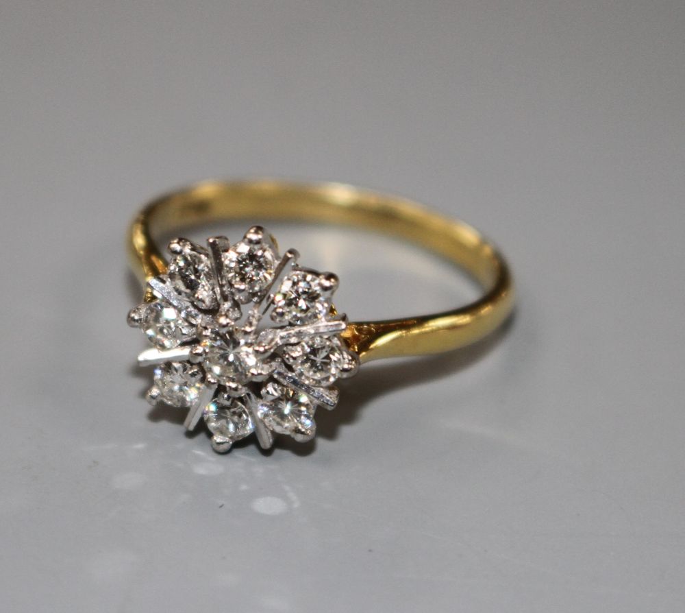 A modern 18ct and nine stone round cut diamond set flower head cluster ring, size P, gross 3.9 grams,